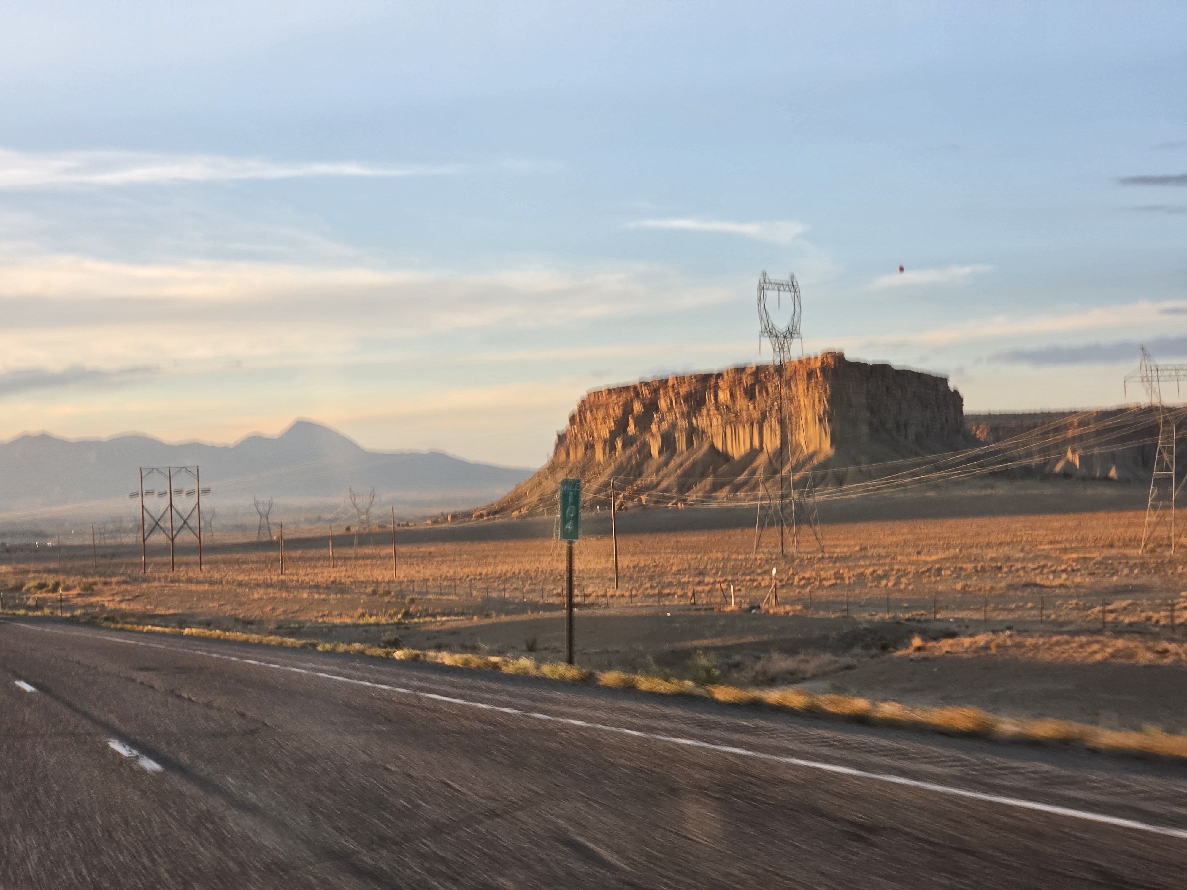 A red sandstone mesa glowing at golden hour along US-491 north of Shiprock