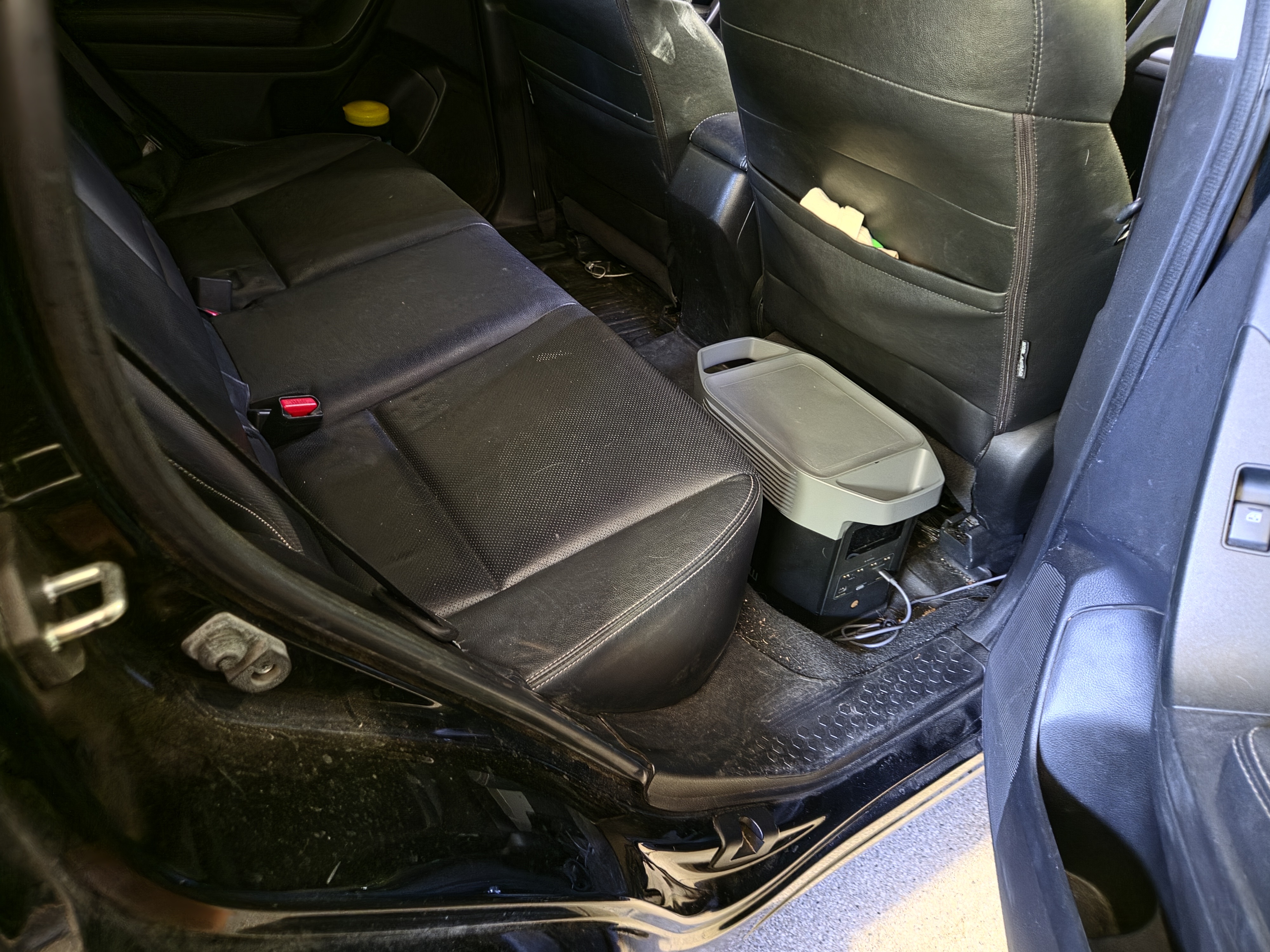 Portable power station sitting on the floor behind the rear seat, plugged in