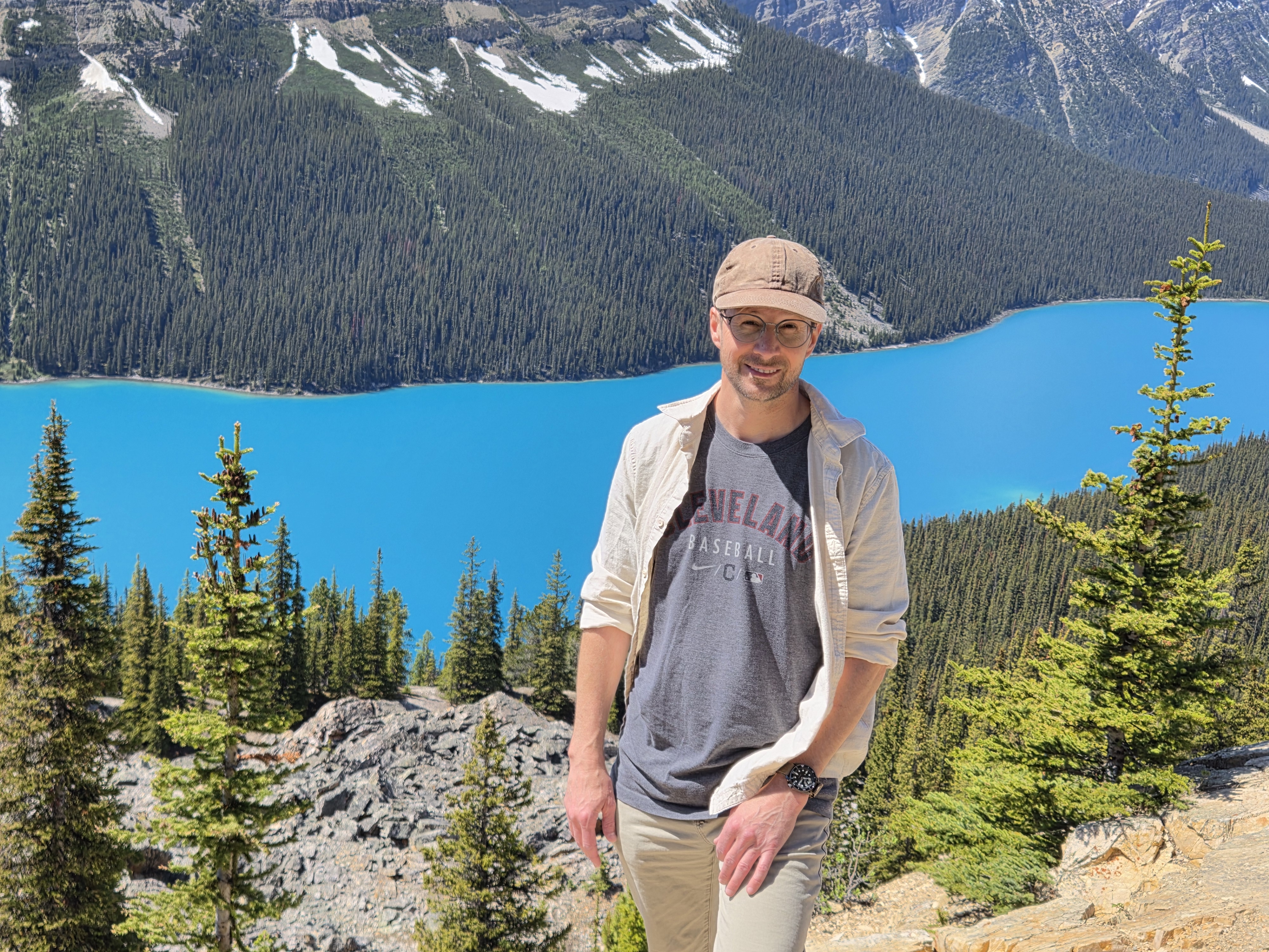 A person standing on the rocky overlook with the turquoise lake and mountains behind them