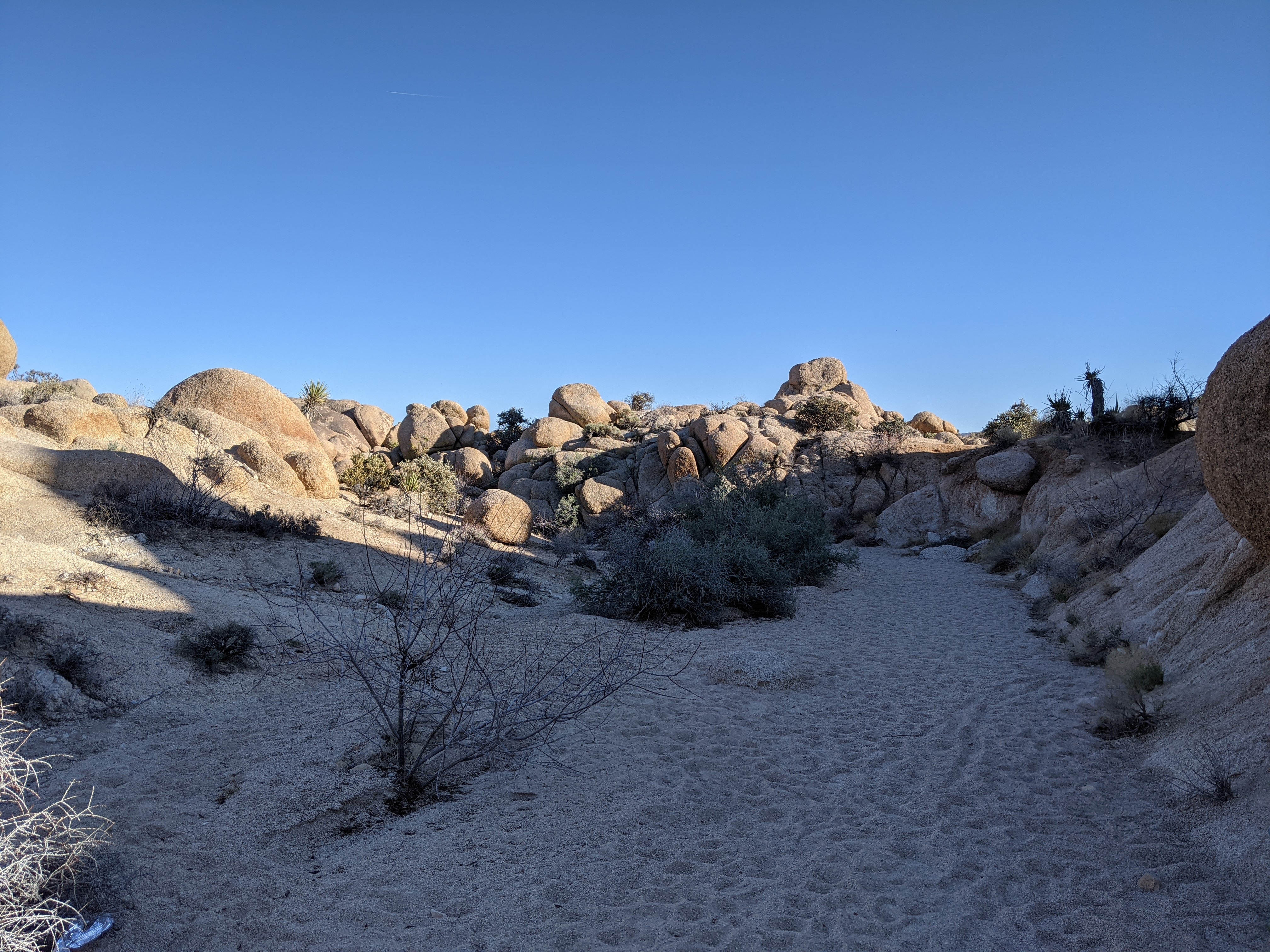 Wide desert wash with boulder field beyond